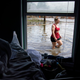 A woman, seen through the window, walks through floodwaters beside her flood-damaged home in the aftermath of Hurricane Ida in Louisiana.